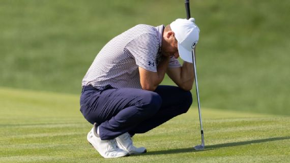 Jordan Spieth grimaces, holding his left‍ shoulder after⁢ a swing.